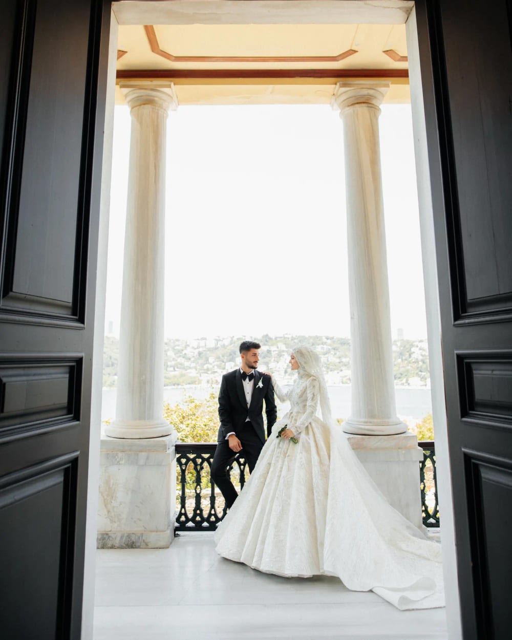 Bride and groom on the columned balcony of the Adile Sultan Palace, looking out over the Bosphorus