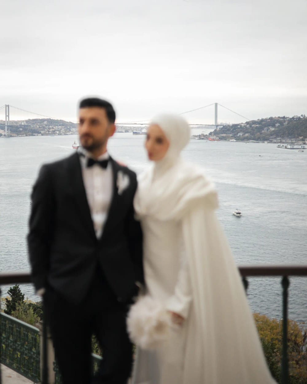 Bride and groom on the terrace of the Adile Sultan Palace, with the Bosphorus and the bridge behind them