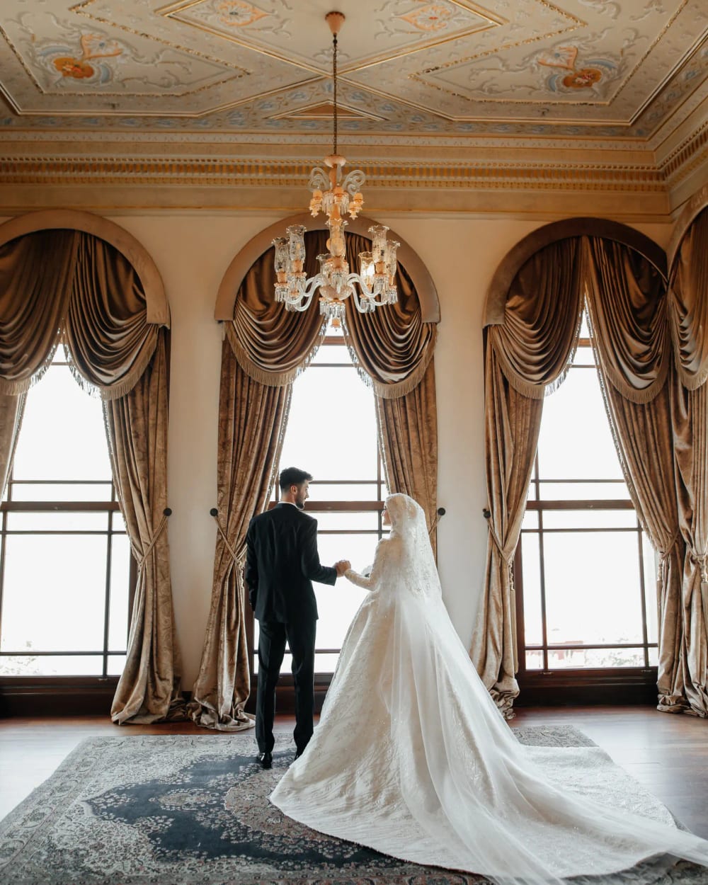 Bride and groom in front of curtained arched windows at the Adile Sultan Palace