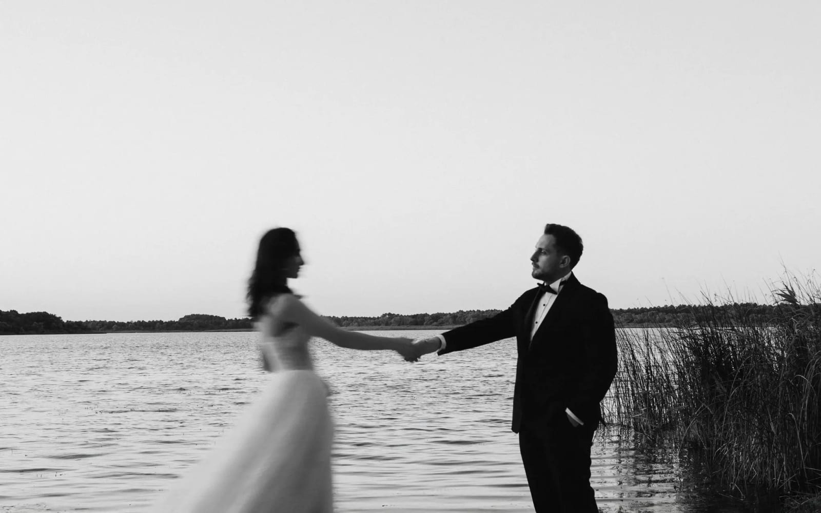 Deniz kıyısında el ele yürüyen gelin ve damat, siyah beyaz dış çekim